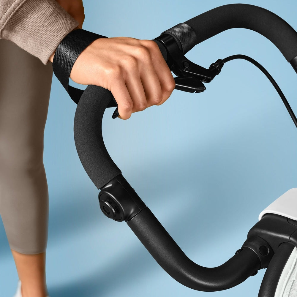 Close-up of the Cybex Avi Spin All Terrain Stroller handlebar grip with padded foam, user gripping securely to steer.