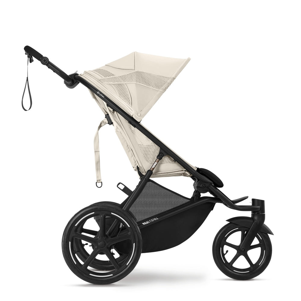 Close-up of the Cybex Avi Spin All Terrain Stroller in beige with large rear wheels shows its sturdy frame as a parent grips the handle.