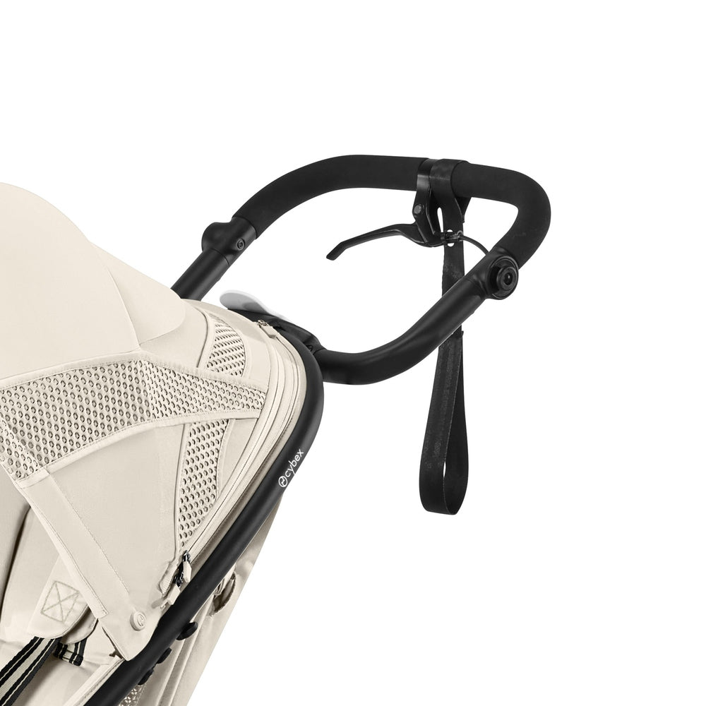 Close-up of the Cybex Avi Spin All Terrain Stroller in beige with black padded handle and ergonomic brake strap.