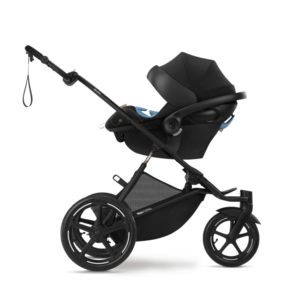 Close-up of the Cybex Avi Spin All Terrain Stroller in black with large wheels and bassinet attached being pushed by a parent.