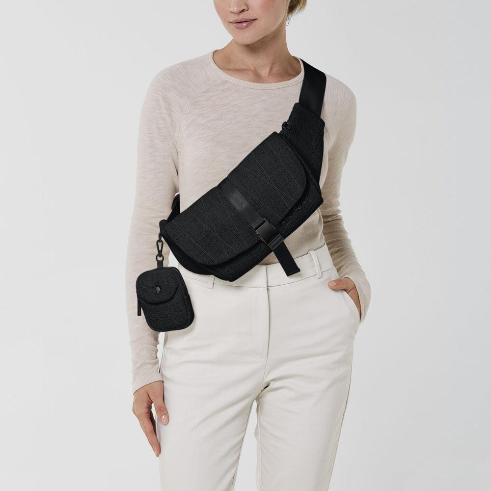 Close-up of the Cybex Belt Bag Boucle black boucle belt bag worn diagonally across the chest with an adjustable strap and a small attached pouch.