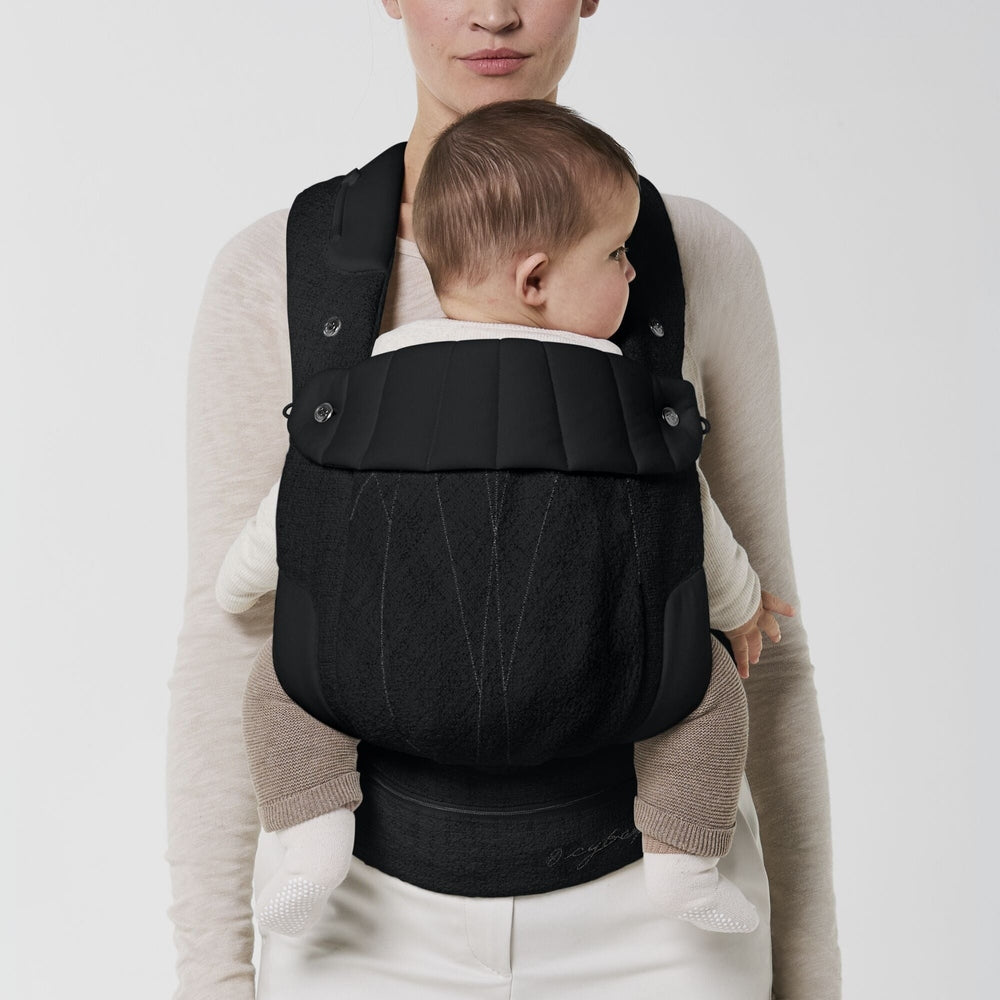 Close-up of the Cybex Coya Carrier Boucle e in black with textured boucle fabric, padded shoulder straps, and wide waistband.