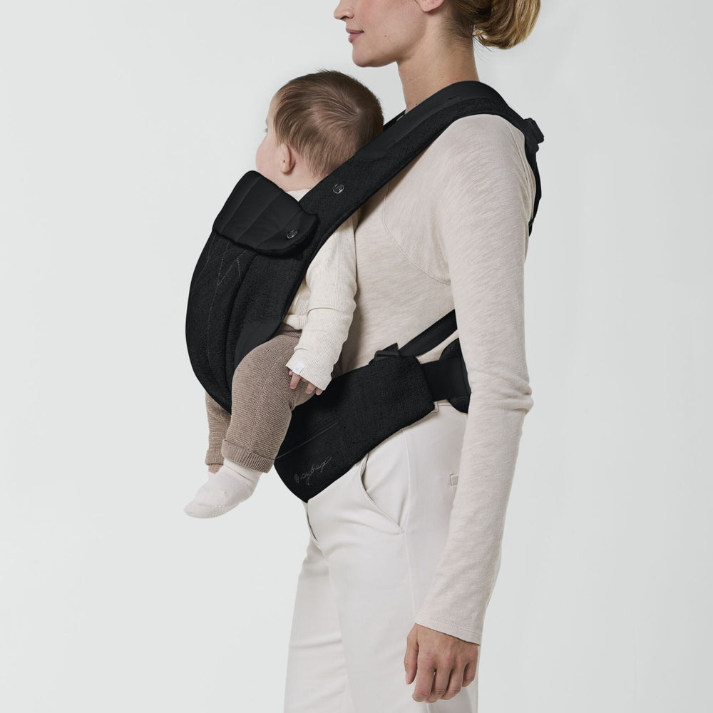 Close-up of the Cybex Coya Carrier Boucle in black with padded shoulder straps, baby seated in front, facing wearer.
