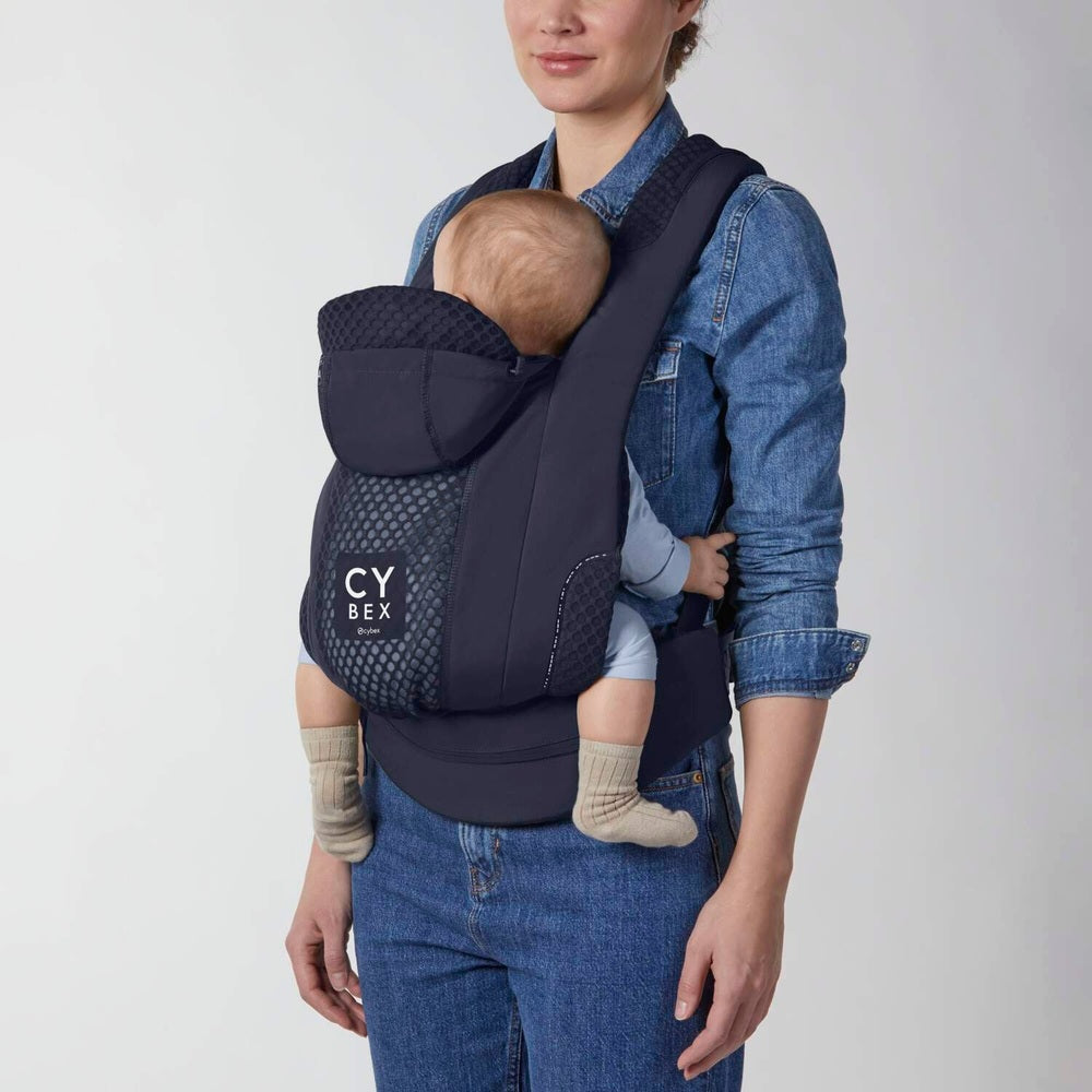 Close-up of the Cybex Coya Carrier in navy with mesh panel, infant inward-facing carried by mother.