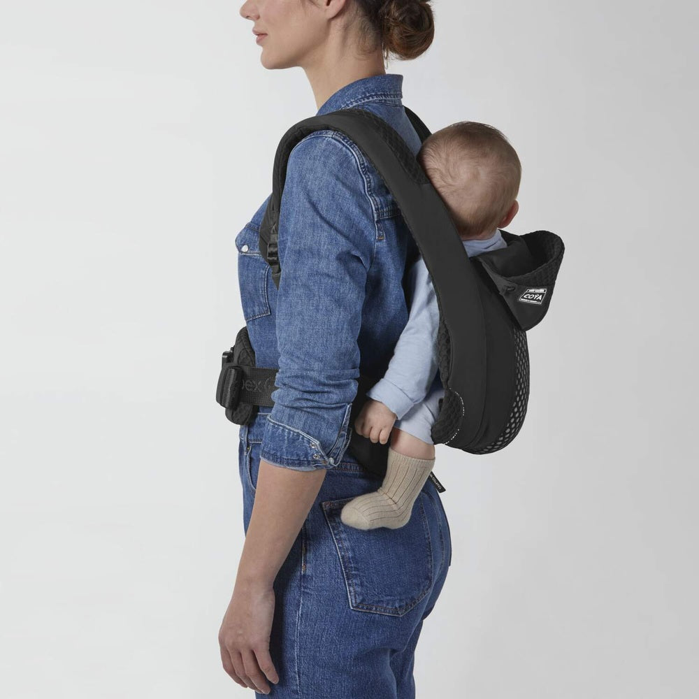 Lifestyle image of the Cybex Coya Carrier in black worn on back by parent with infant.