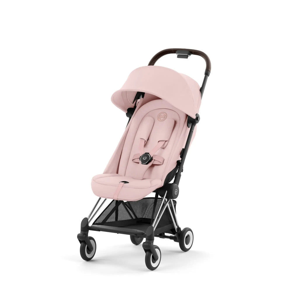 Lifestyle image of the Cybex Coya Chrome Frame Stroller in pink with canopy and 5-point harness, ready to push.