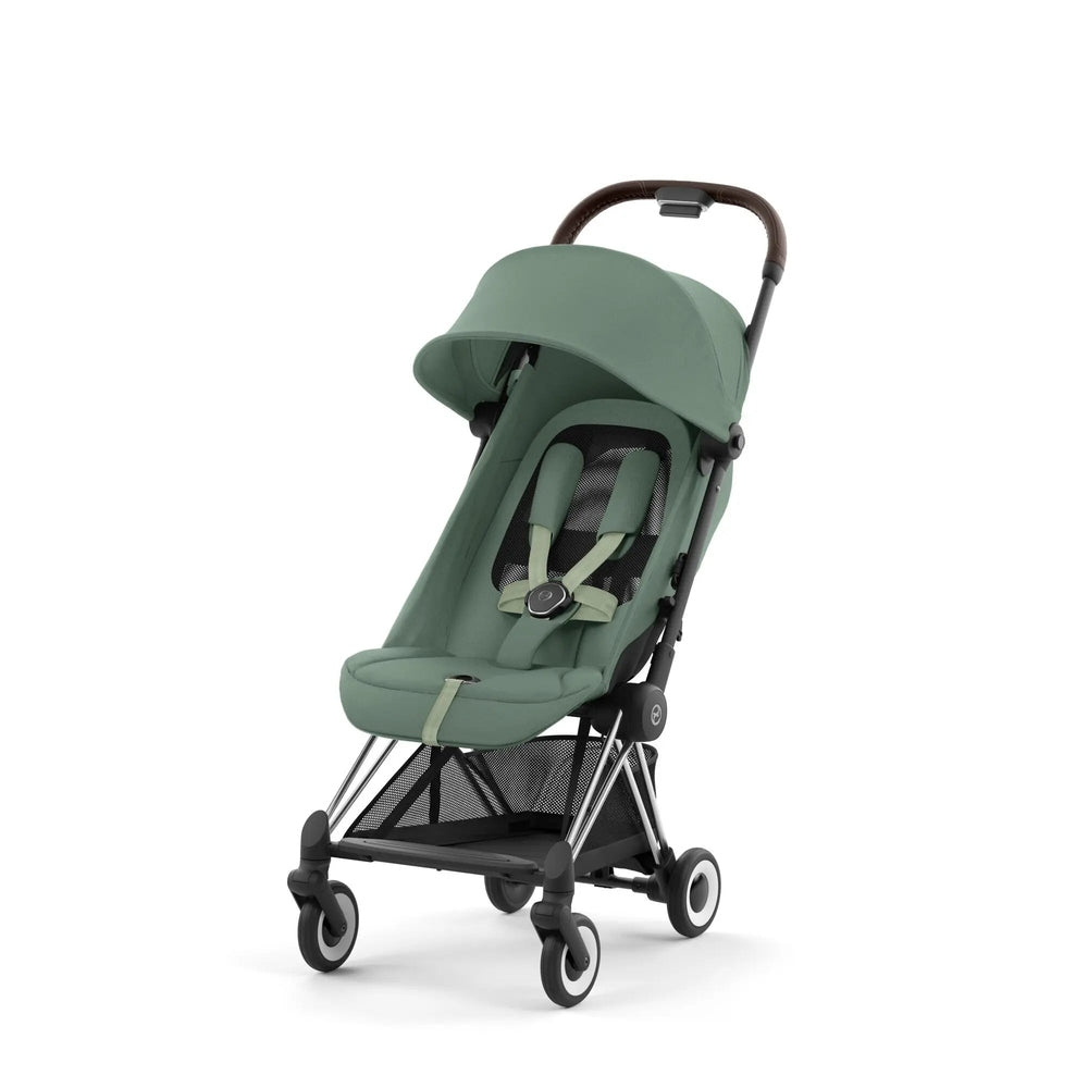 Lifestyle image of the Cybex Coya Chrome Frame Stroller in green with canopy raised and 5-point harness in use.
