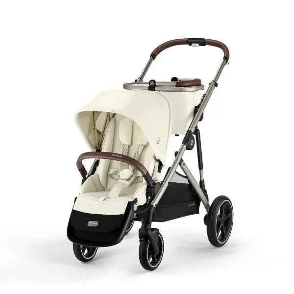 Lifestyle image of the Cybex Gazelle S V2 Stroller in cream with brown accents; canopy extended over twin-seat area, showing sturdy aluminum frame.
