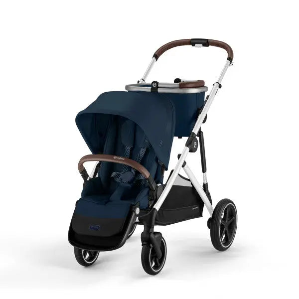 Lifestyle image of the Cybex Gazelle S V2 Stroller in navy blue with brown leatherette accents and white frame, canopy extended.