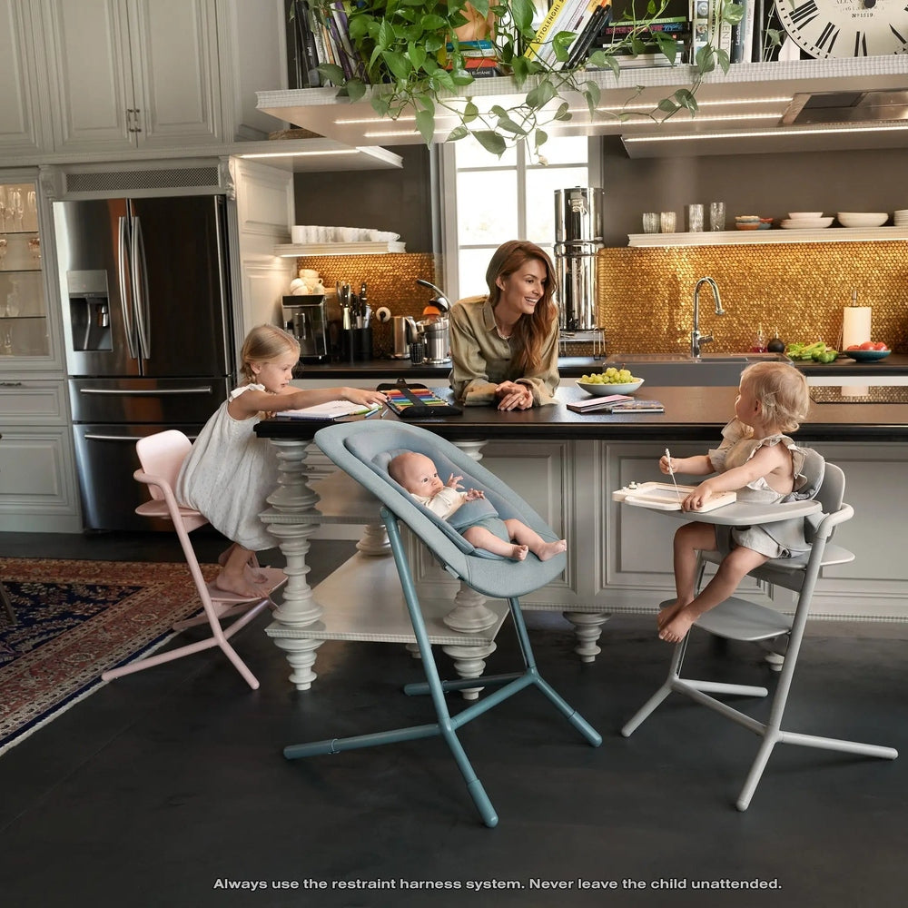 Lifestyle image of the Cybex Lemo 2 Chair high chairs in blue-gray, pink, and gray around a kitchen island with kids eating.