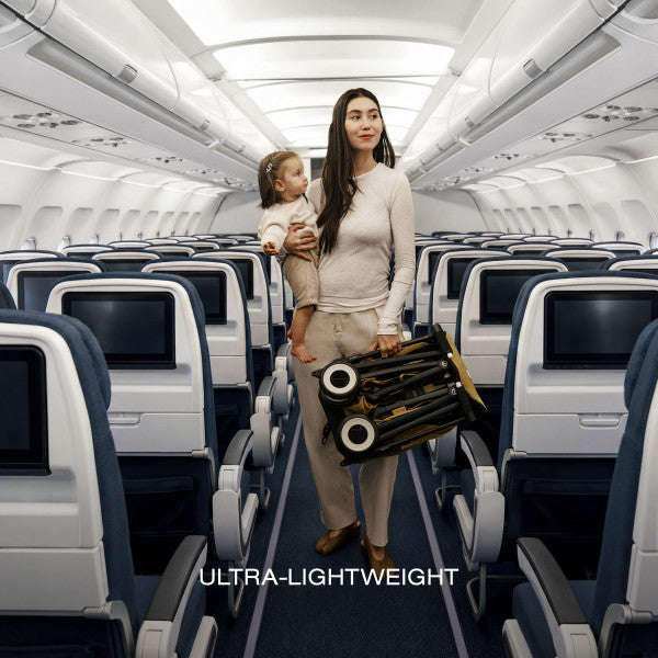 Cybex Libelle Ultra-compact Stroller in Cinnamon Yellow folded and carried through an airplane cabin with a child
