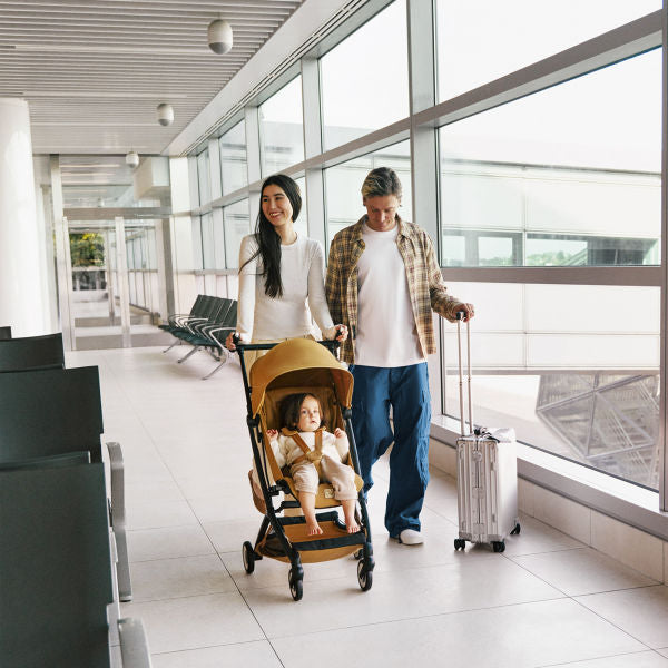 Cybex Libelle Ultra-compact Stroller in Cinnamon Yellow being pushed through an airport terminal