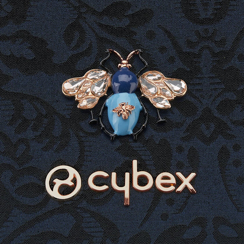 Close-up of CYBEX Platinum limited-edition jacquard fabric with jewel beetle embroidery and metallic bee appliqué.