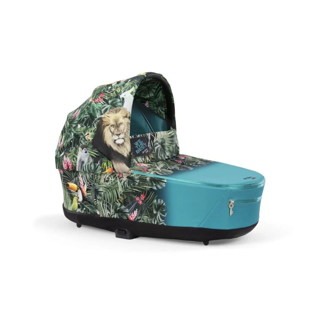 Studio product image of the Cybex Platinum Priam Carry Cot Limited Edition with limited edition tropical jungle print attached to teal base chassis with zip pocket.