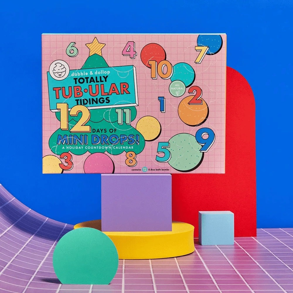 Dabble & Dollop 12 Days of Mini Drops Bath Bomb Countdown Calendar on a bright display, with bold numbers and colorful circles.