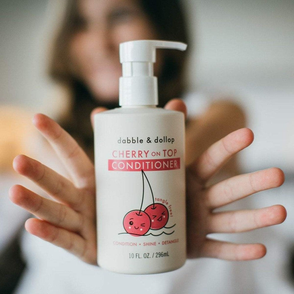 Dabble & Dollop Cherry on Top Conditioner bottle with pump, white label, cherry cartoon being held.