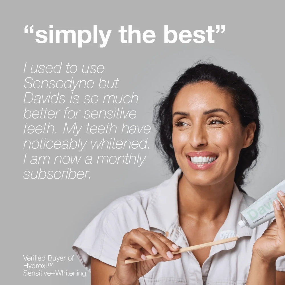 DAVIDS Toothpaste Sensitive & Whitening Fluoride Free Peppermint; smiling woman squeezes toothpaste onto a toothbrush.