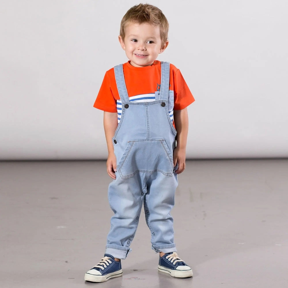 Deux Par Deux denim overall on a smiling toddler in an orange tee, with shoulder straps and front pocket.