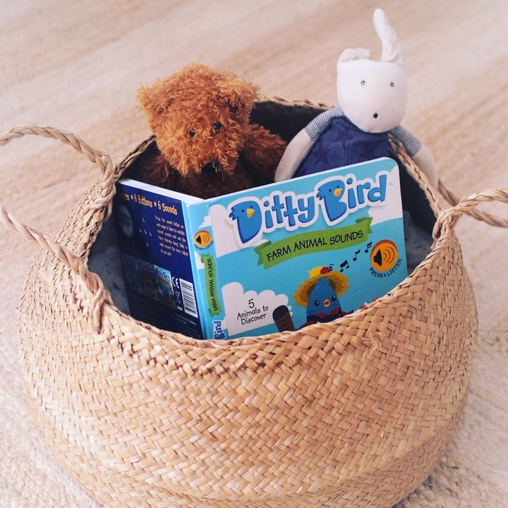 Ditty Bird Farm Animal Sounds USB-C Rechargeable book nestled in a woven basket with two plush toys.