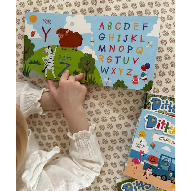 Ditty Bird Sound Book Fun Alphabet USB-C Rechargeable: child interacts with colorful alphabet board beside Ditty Bird boxes