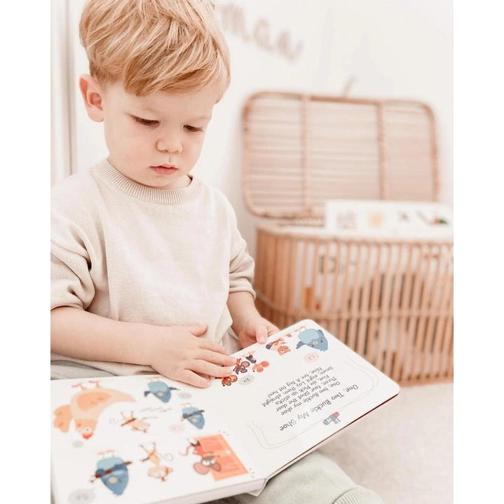 Ditty Bird Sound Book Learning Songs USB-C Rechargeable toddler turning a colorful picture book, exploring animals.