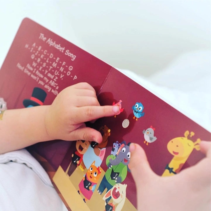 Ditty Bird Sound Book Learning Songs USB-C Rechargeable; toddler flips colorful pages, engaging with music.