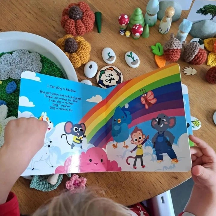Ditty Bird Sound Book Nature Songs USB-C Rechargeable; child turns bright rainbow-spanned pages featuring animal characters.