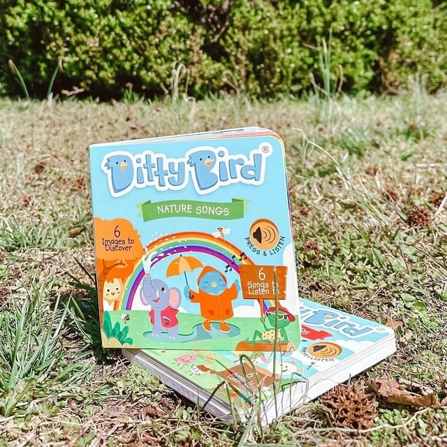 Ditty Bird Sound Book Nature Songs USB-C Rechargeable toy; two colorful boxes outdoors on grass, with press & listen cue.