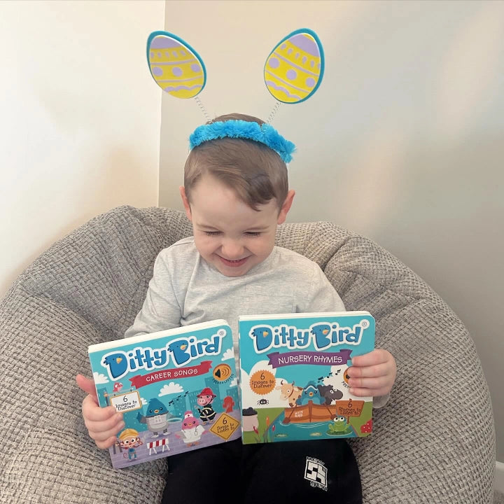 Ditty Bird Sound Book When I Grow Up Career Songs USB-C Rechargeable-smiling toddler holds a two-book set on a cozy bean bag.