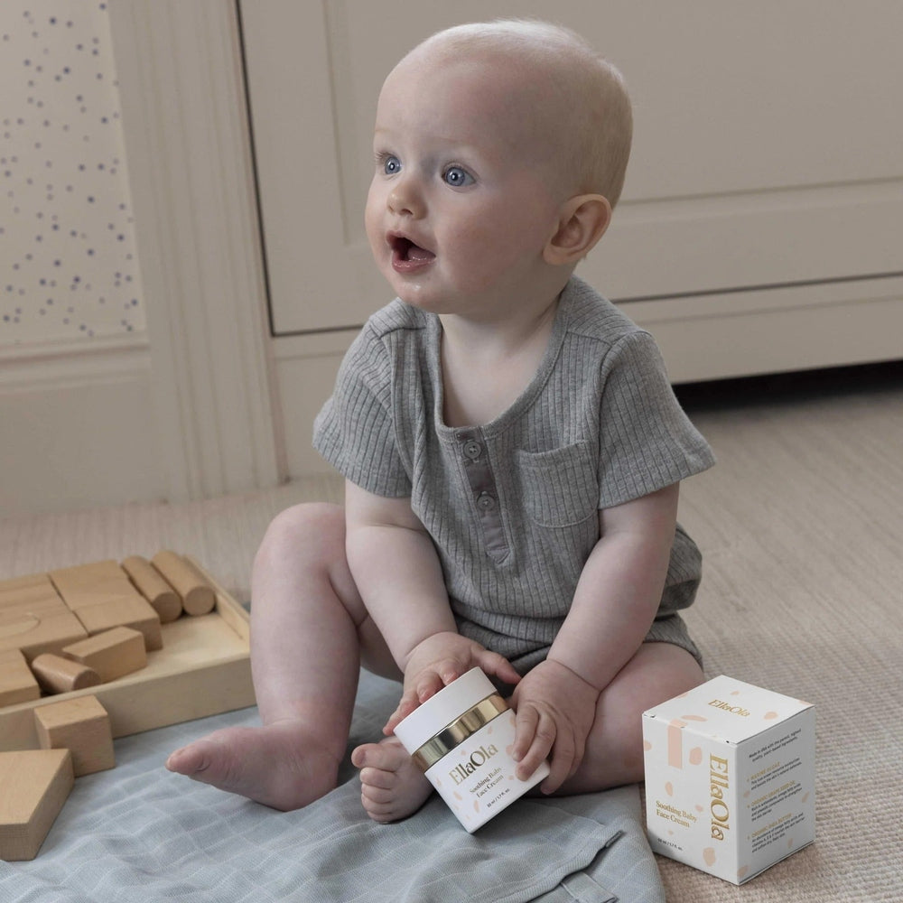 EllaOla Fragrance Free Moisturizing Baby Face Cream 50ml; baby sits on a mat, holding the jar beside the box.