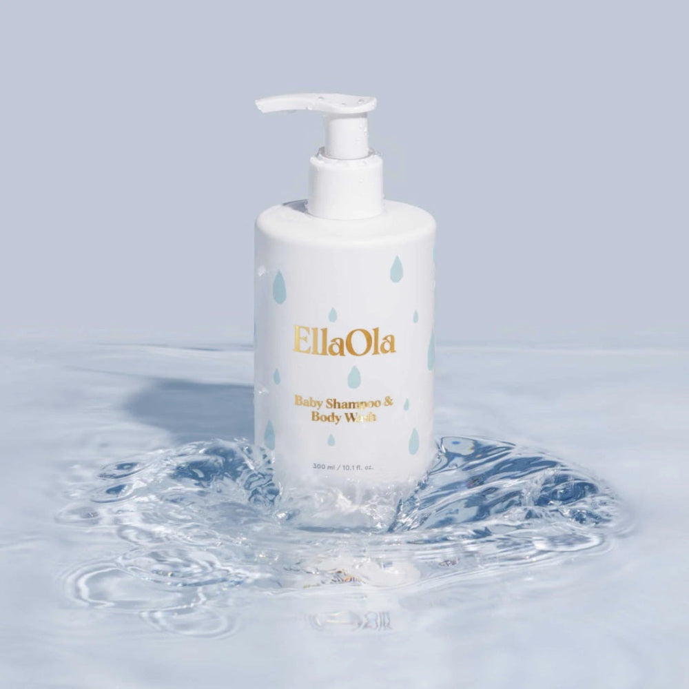 EllaOla Tear Superfood Baby Shampoo & Body Wash 300ml pump bottle, white with blue droplets, resting in a splash.
