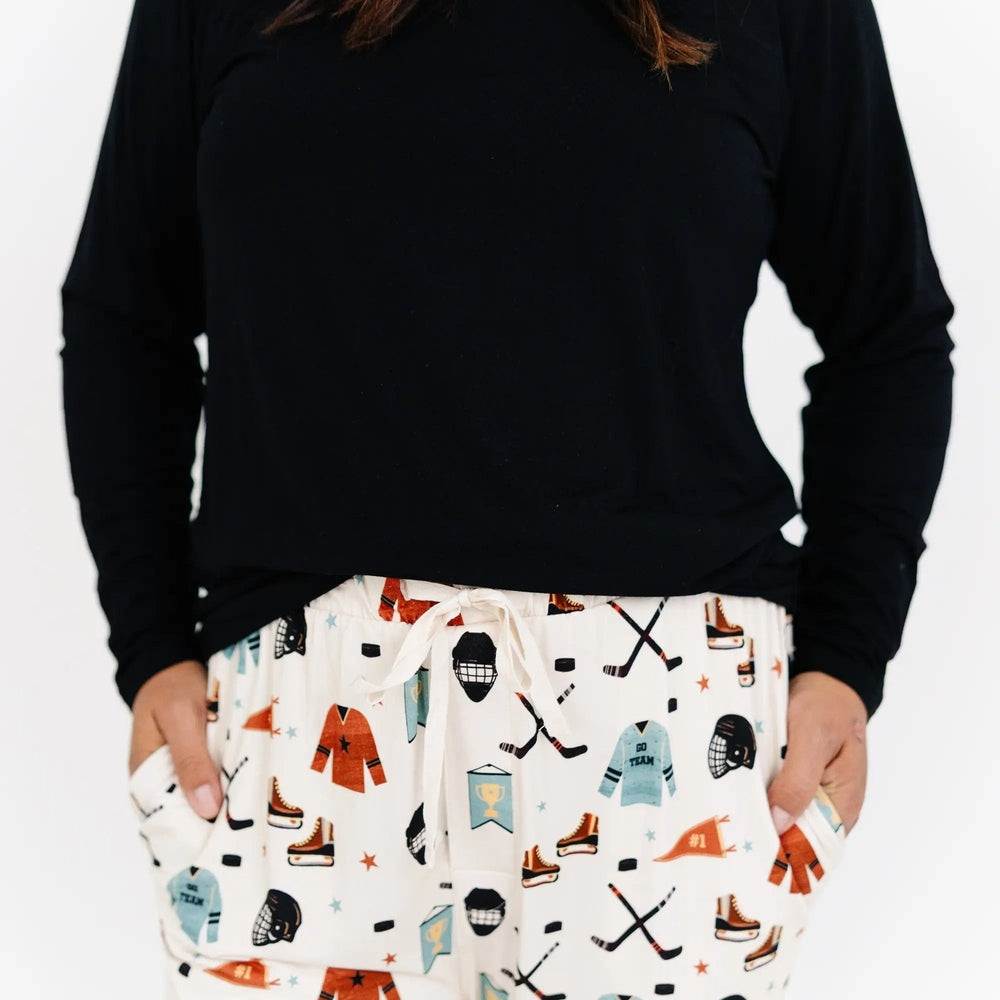 Woman wearing a black long-sleeve shirt and patterned pants on a white background