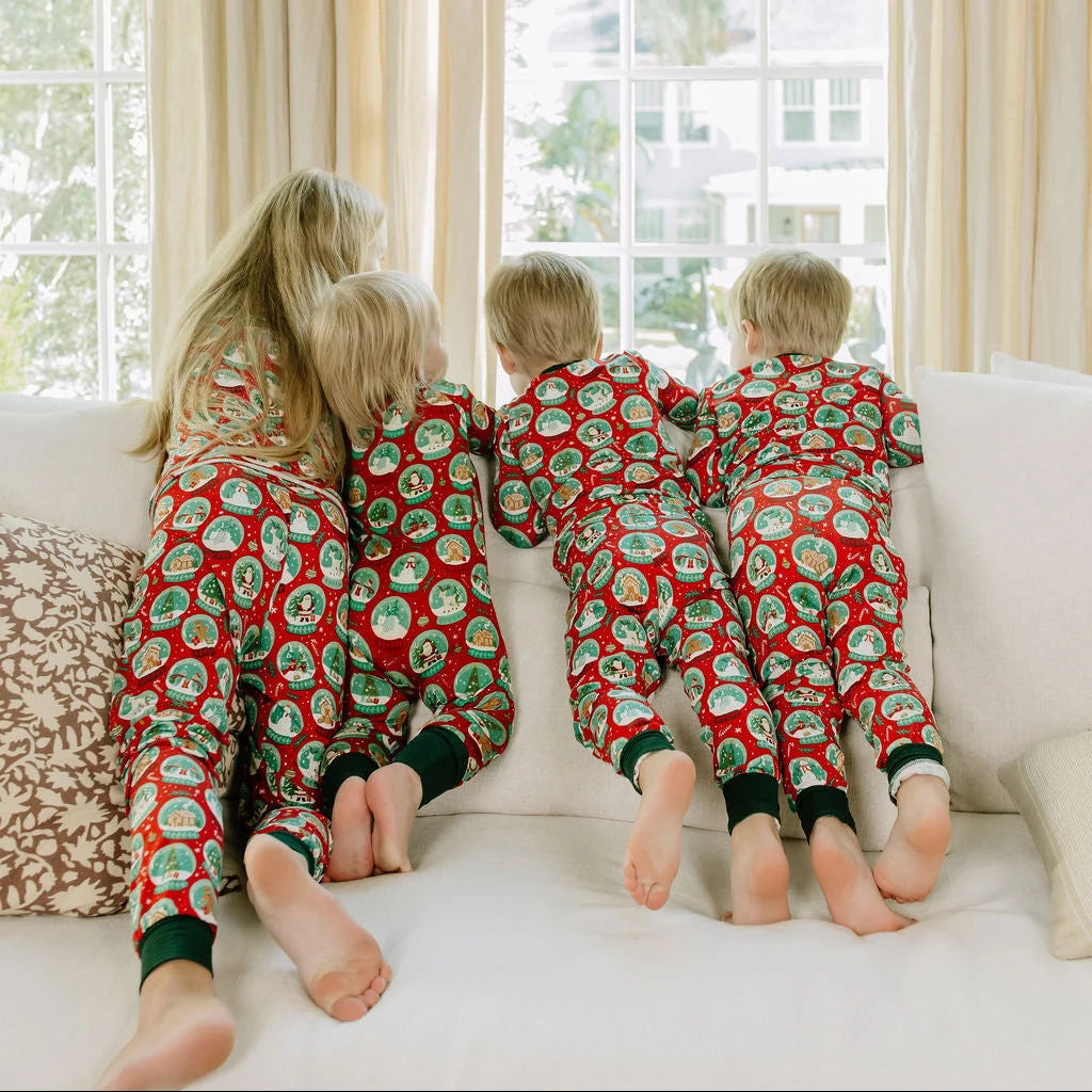 Emerson and Friends Let It Snow kids bamboo pajamas, children showing the back of matching snow-globe pajamas by a window