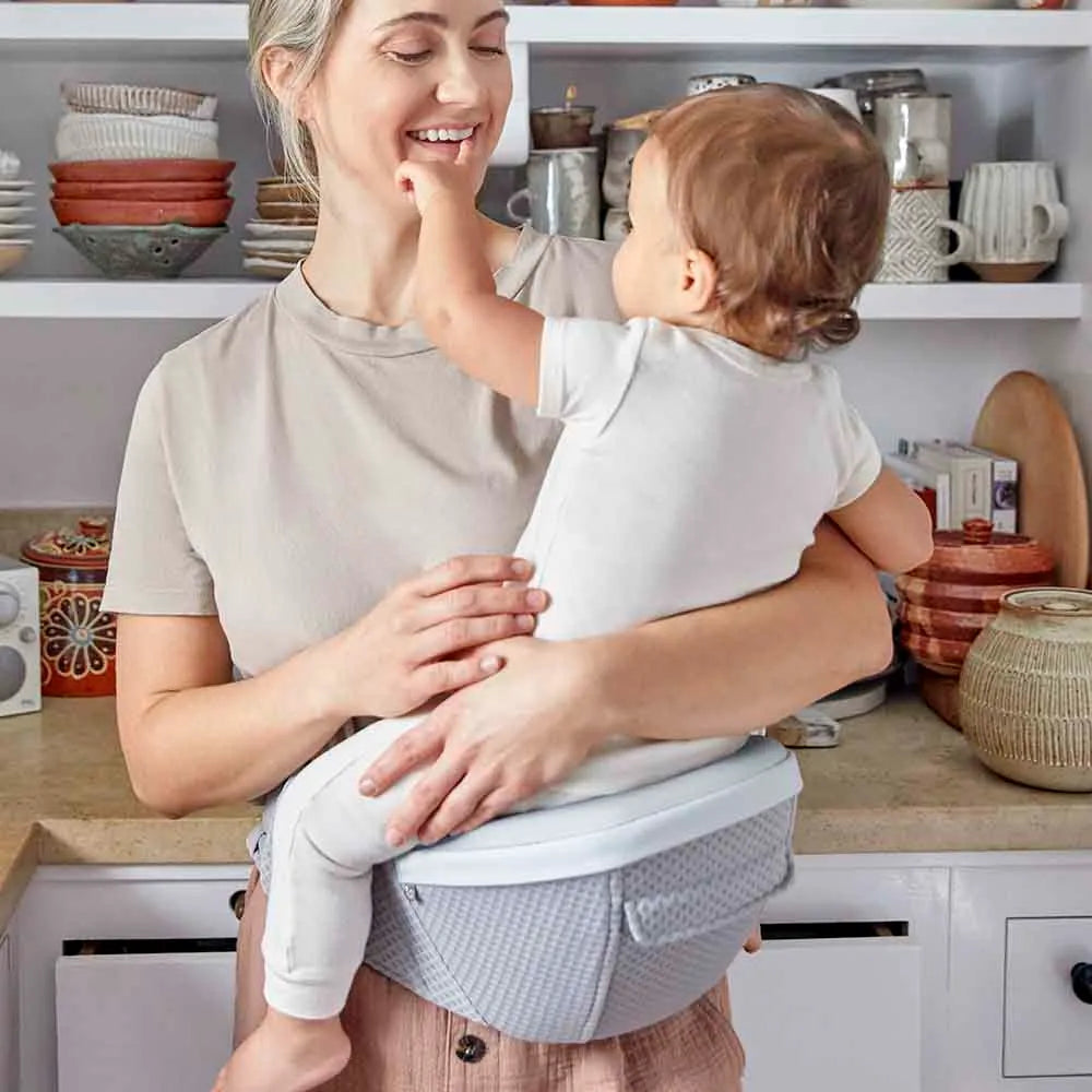 Ergobaby Alta Hip Seat Baby Carrier in light gray, mom carries baby on her hip with secure seat.