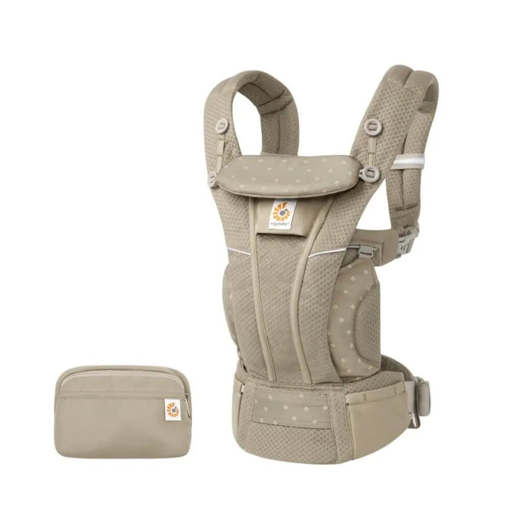 Ergobaby Omni Breeze baby carrier in beige worn on a model, showing padded straps and waist belt with matching beige pouch.