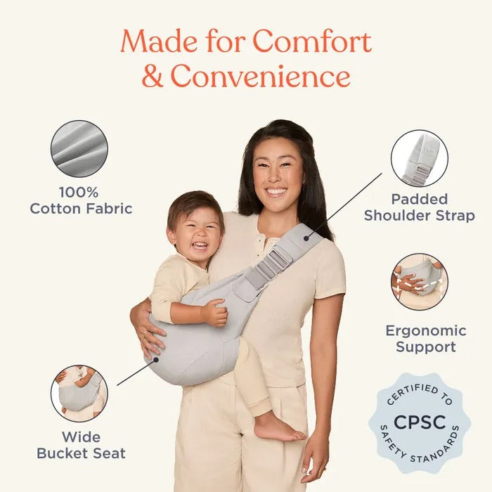 ERGOBABY Upsie Sling Carrier in gray being worn by a mom, showing padded shoulder strap, wide bucket seat, ergonomic support.