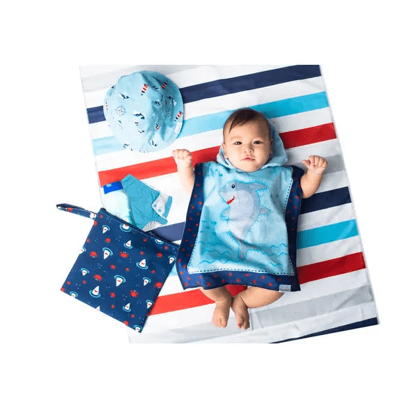 Flapjackkids Kids 2 Sided Wet Bag set, baby on striped mat with navy fish-print bag and shark-themed towel.
