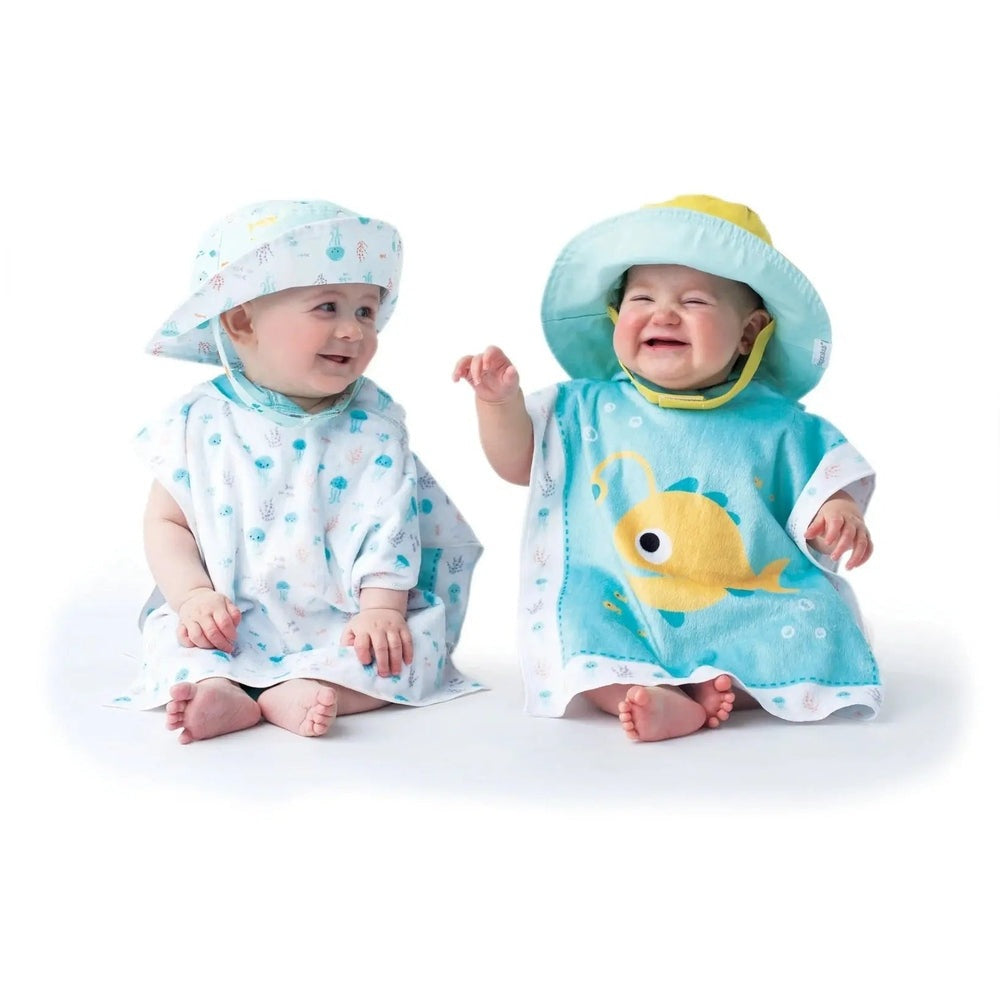 Flapjackkids Reversible Kids Sun Hat Fish & Jellyfish, two babies in aqua sea-print outfits smiling at each other.