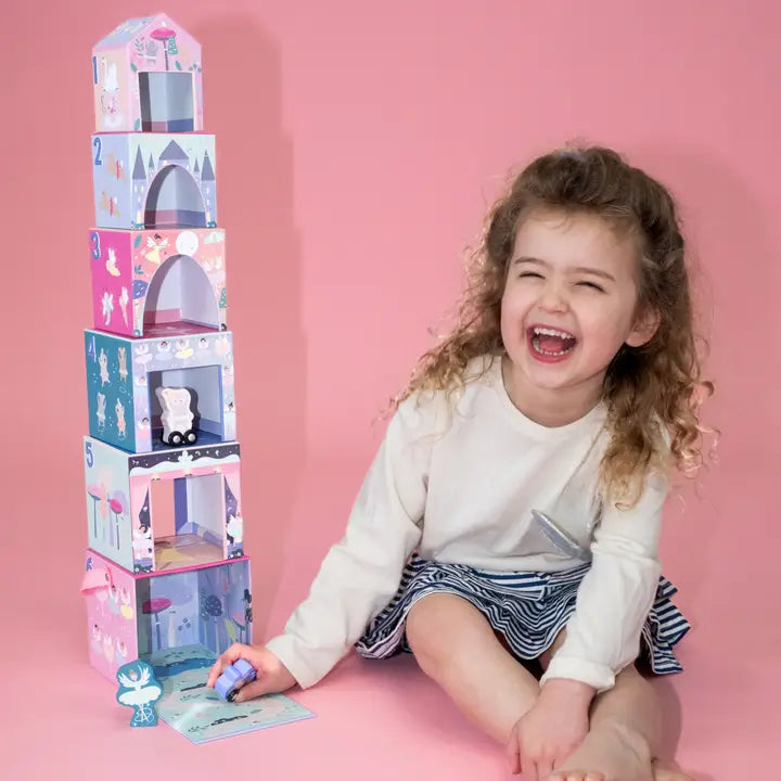 Floss and Rock Stacking Cubes tower; a joyful girl places a pastel cube onto the stacked blocks in play.