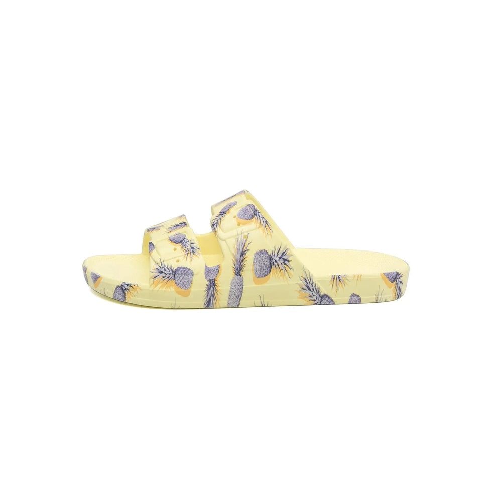 Freedom Moses Prints Pina Colada Sugar slides, yellow two-strap sandals with pineapple print.