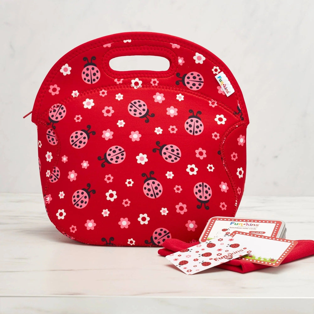 Red neoprene insulated lunch bag with pink ladybugs and white flowers pattern; handle and zipper.