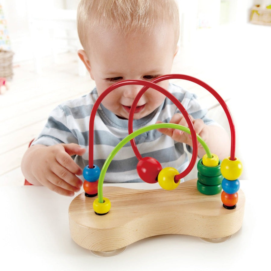 Hape Double Bubble bead maze toy; toddler guides colorful wooden beads along curved arches on a wooden base.