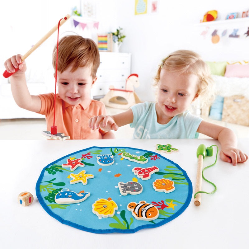Hape Fishing Game: round blue sea-themed fishing mat with wooden rods and colorful magnet fish, two kids playing.