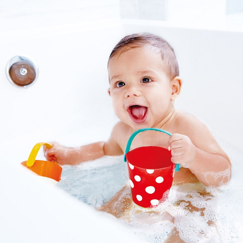 Hape Happy Buckets Set: baby splashes bath with red polka-dot bucket, teal handle, and yellow shovel.