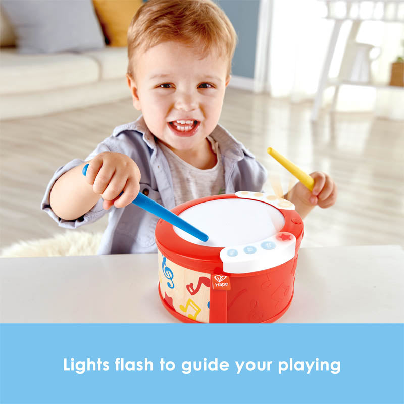 Hape Learn To Play Drum red toy drum with white lid and blue/yellow sticks, child playing