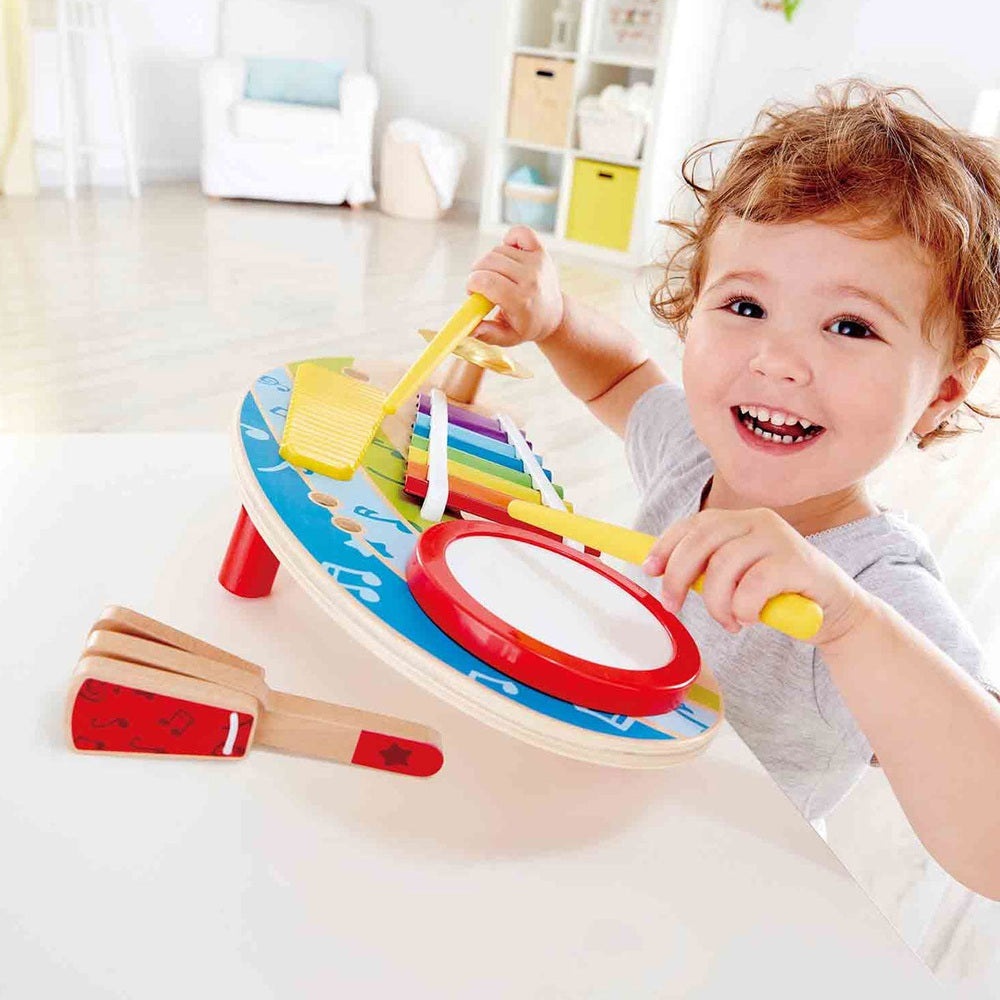 Hape Mighty Mini Band toy set with colorful xylophone bars and drum, child tapping with yellow mallets