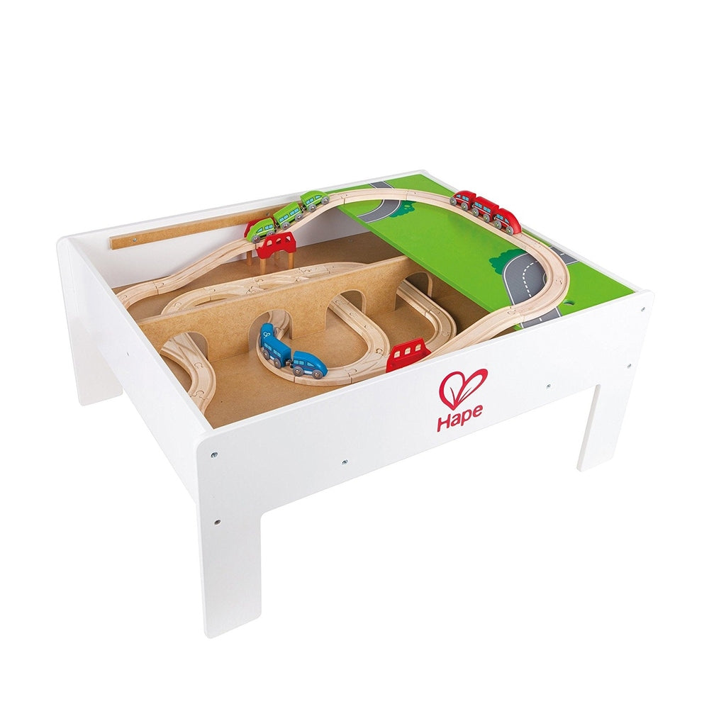 Hape Reversible Train & Storage Table in white with wooden track looping over a green road playfield and toy cars.