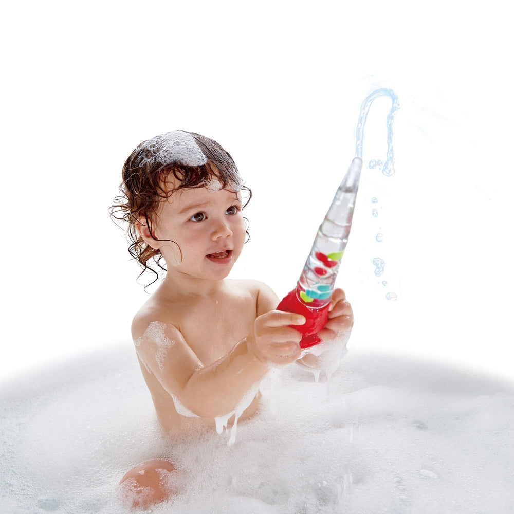 Hape Squeeze & Squirt bath toy, colorful plastic bottle held by a baby in bubbles