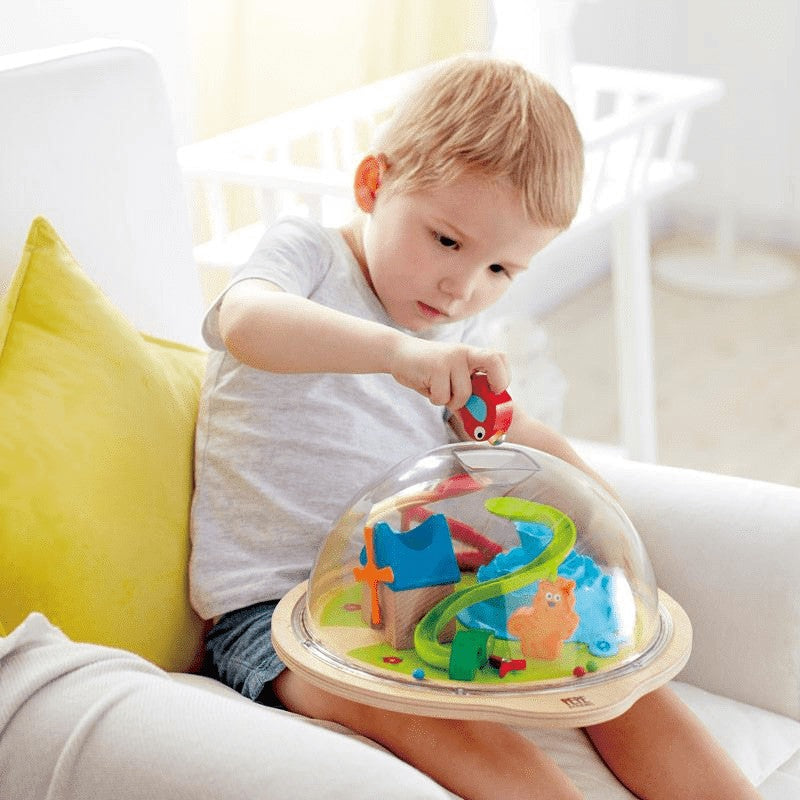 Hape Sunny Valley Adventure Dome with clear dome and colorful tracks; toddler playing.