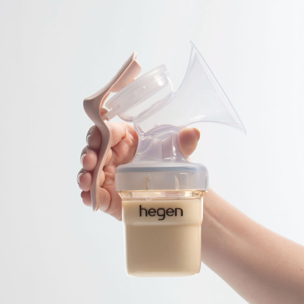 HEGEN PCTO manual breast pump module in clear and beige with peach handle, held in hand